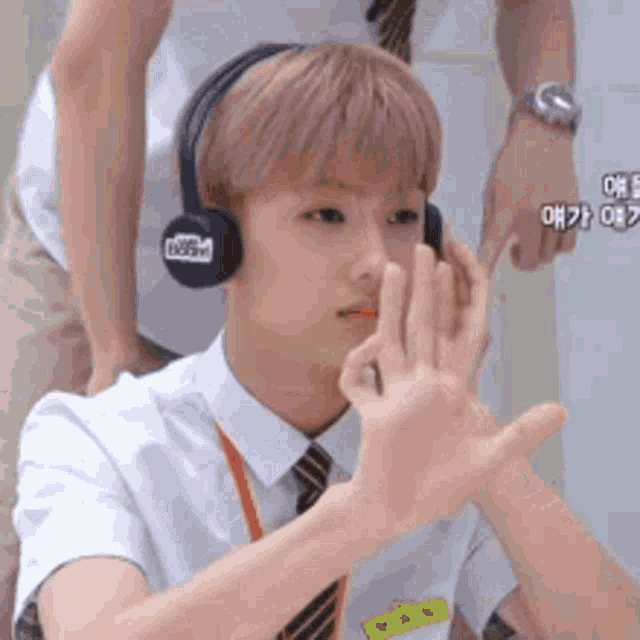 a man wearing headphones and a tie is making a hand gesture .