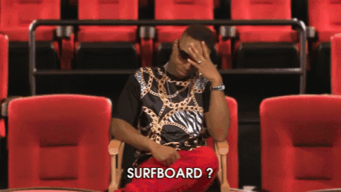 a man sitting in a row of red seats with the word surfboard written on the screen