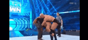 a man is wrestling another man on a wrestling ring while a referee watches .
