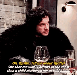 a man in a fur coat is sitting at a table with glasses of wine
