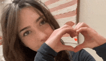 a young woman is making a heart shape with her hands .