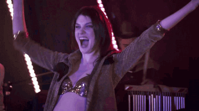 a woman is dancing with her arms in the air in a club