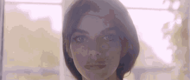 a close up of a woman 's face with the sun shining through the window behind her .