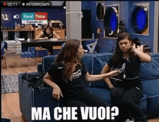 two women are sitting on a blue couch with the caption ma che vuoi ?