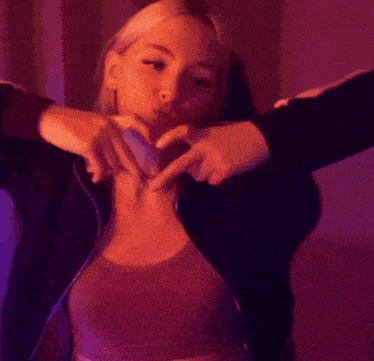 a woman making a heart with her hands on her chest