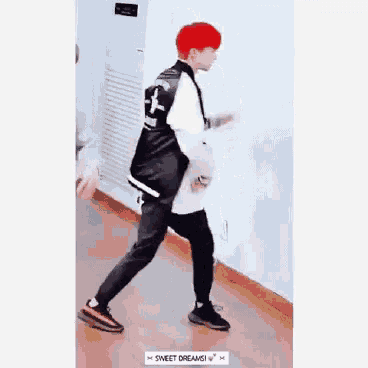 a man with red hair is walking down a hallway next to a wall .