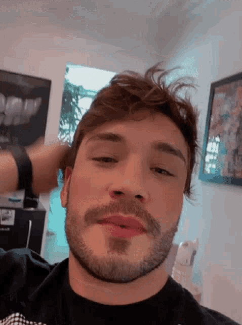 a man with a beard wearing a black shirt is looking at the camera