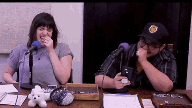 a man and a woman are sitting at a table with microphones laughing