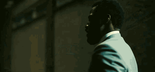 a man with a beard wearing a suit and tie is walking down a dark street at night .