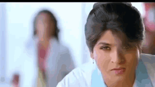 a woman in a white coat is looking at the camera with a woman in a lab coat behind her .