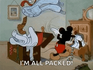 mickey mouse is standing next to a trunk filled with clothes and saying `` i 'm all packed ! ''