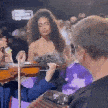 a woman in a strapless dress is playing a violin while a man plays an accordion .