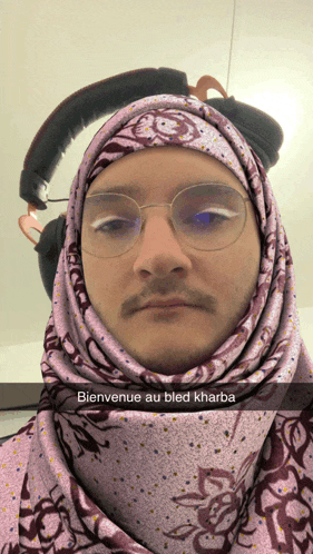 a man wearing glasses and a purple scarf with the words bienvenue au bled kharba