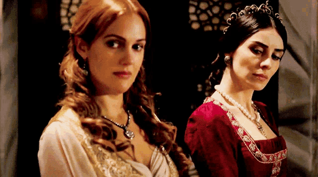 two women standing next to each other with one wearing a red dress