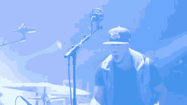 a man playing drums in front of a microphone with a blue background