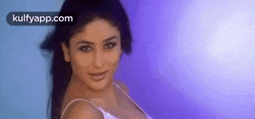 a woman in a white tank top is standing in front of a blue wall .