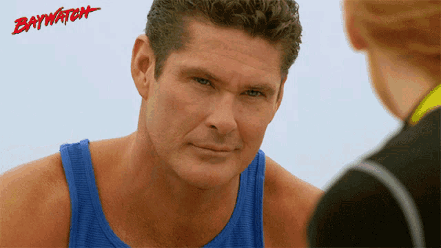 a man in a blue tank top with the word baywatch on the bottom right