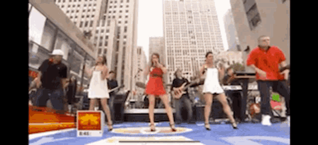 a group of people are dancing on a stage in a city .