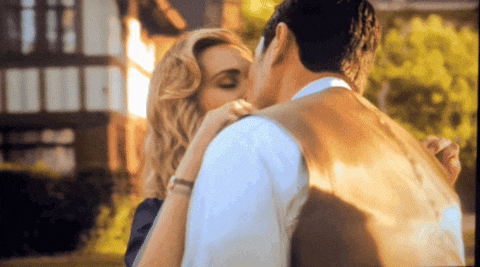 a man and a woman are kissing in front of a building