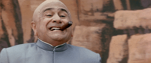 a bald man is smoking a cigar in front of a wall