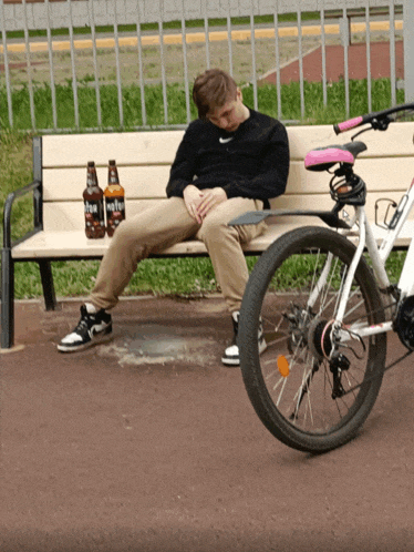 a man is sitting on a bench with two bottles of beer on it