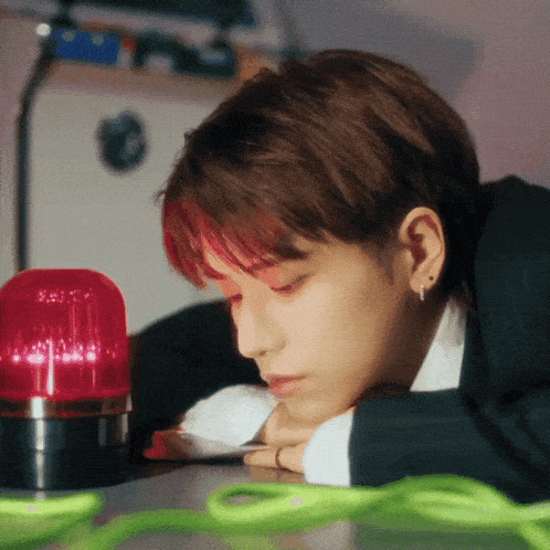 a young man with red hair is laying on a table with his head on his hands