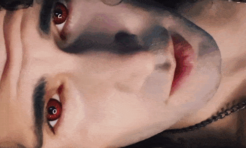 a close up of a man 's face with red eyes and black eyebrows .