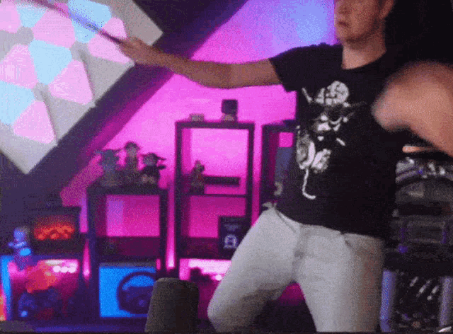 a man in a black shirt with a skeleton on it stands in front of a pink wall