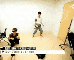 a man and woman are dancing in a room with chinese writing on the wall behind them