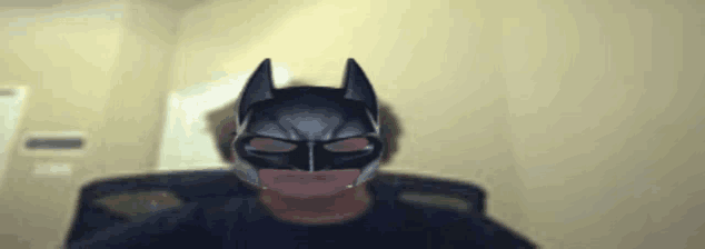 a man is wearing a batman mask and looking at the camera