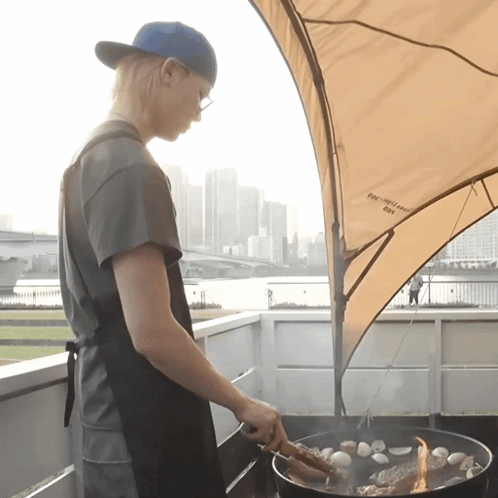 a man is cooking on a grill under an umbrella that says eagle scout