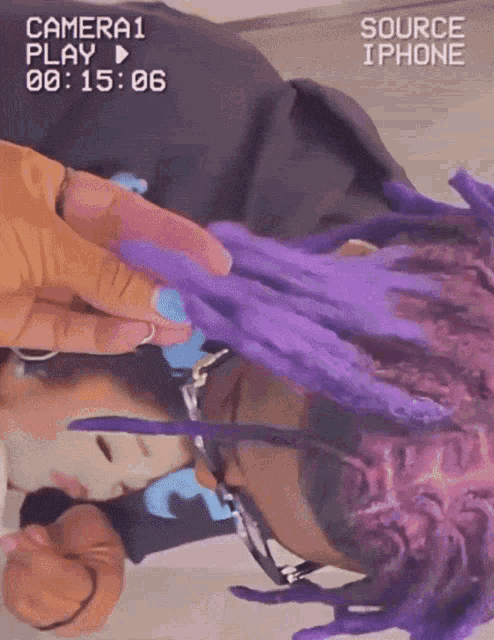 a person with purple dreadlocks is being filmed by a camera that says source iphone