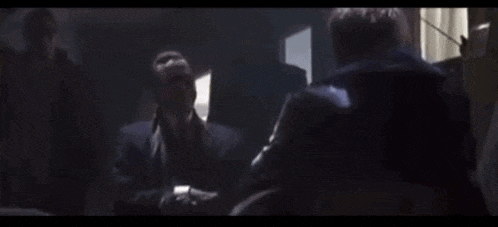 a man in a suit and tie is standing in front of a mirror .
