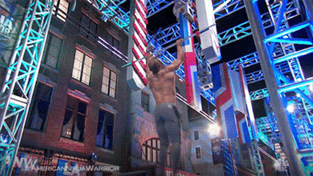 a man without a shirt is doing a pull up on a bar .