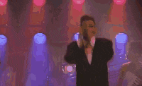 a man in a tuxedo is dancing on a stage in a club .