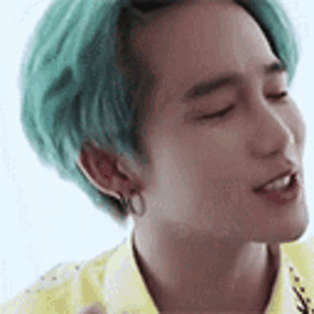 a close up of a man with green hair wearing a yellow shirt .