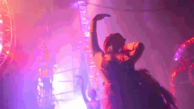 a woman in a feathered dress is dancing in a dark room