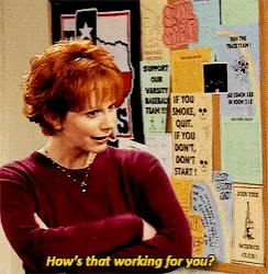 a woman with red hair is standing in front of a bulletin board that says how 's that working for you ?