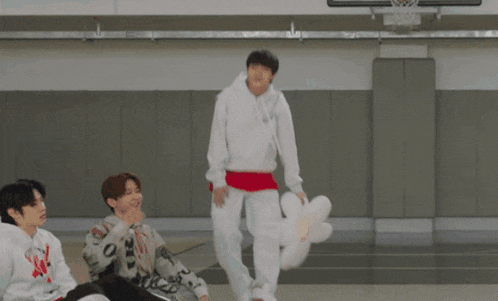 a group of young men are dancing in a gym with korean writing on the bottom right