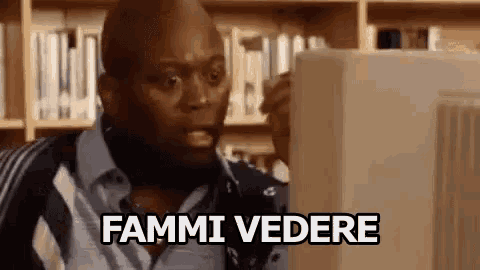 a man is looking at a computer screen and saying fammi vedere in a library .
