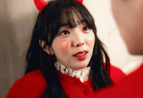 a girl wearing devil horns and a red shirt