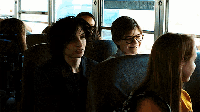 a group of people sitting on a school bus with the word emergency on the side