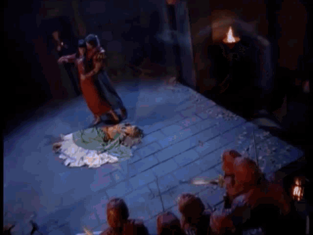 a man in a red dress is dancing with a woman in a green dress