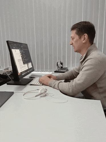 a man sits at a desk in front of a computer monitor that says microsoft on it