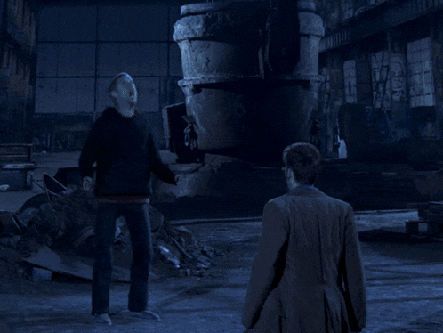 two men are standing in a dark room with blue lights coming out of them