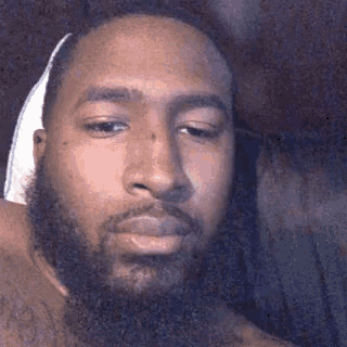 a man with a beard is wearing a bandage on his head and looking at the camera .