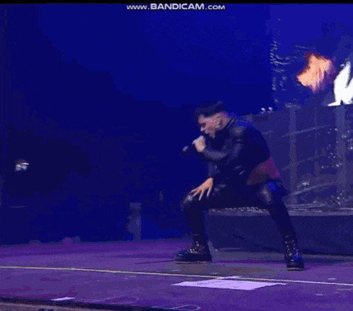 a man is singing into a microphone on a stage with the words www.bandicam.com visible in the corner
