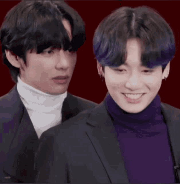 two young men in suits and turtlenecks are laughing together .