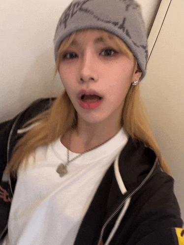 a woman wearing a gray beanie and a white shirt