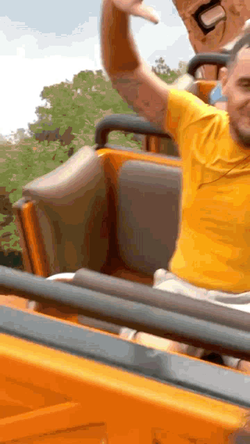 a man in a yellow shirt is riding a rollercoaster